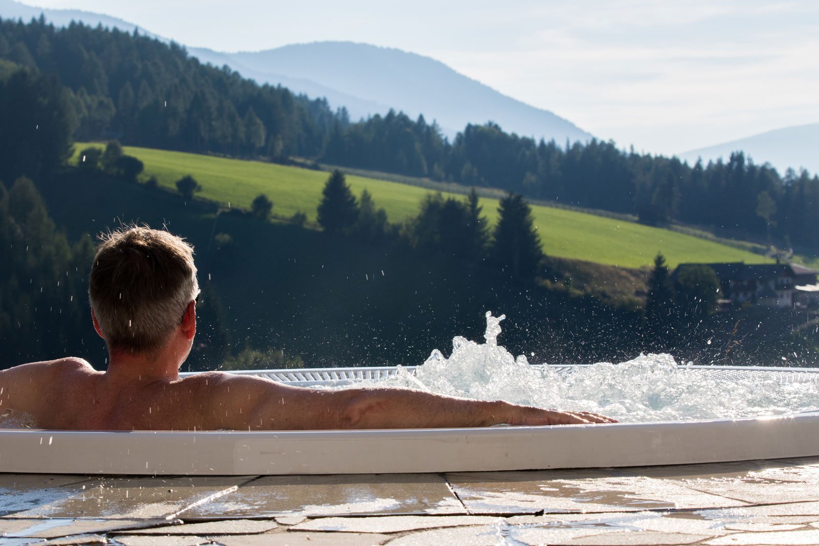 Man-using-hot-tub-overlooking-mountains Cheap inflatable hot tub vs non-inflatable hot tub